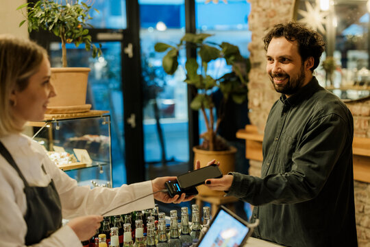 Customer paying by smartphone at cafe counter during leisure time