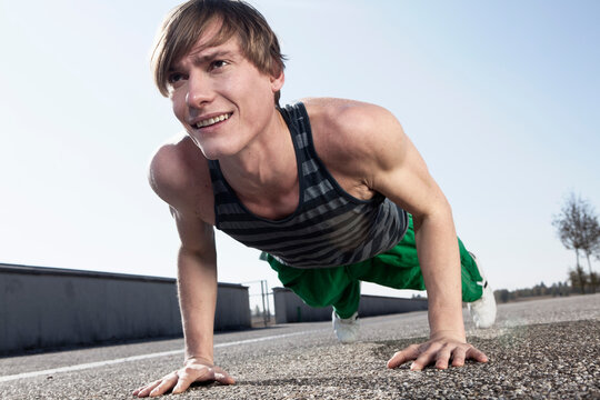 Smiling athlete doing push up outdoors on urban street in Munich