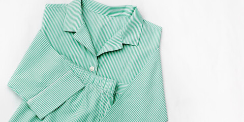 Green striped Pajamas on white sheet background, close up textured banner. Top view sleepwear female from soft cotton mint colored. Cozy pyjamas of shirt and shorts for comfort rest, copyspace