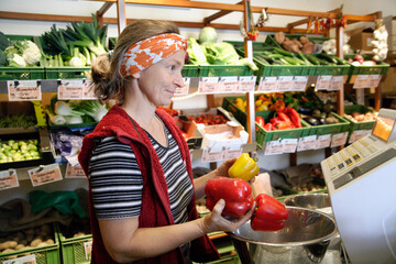 Shopkeeper weighing red and yellow pepper in organic food store