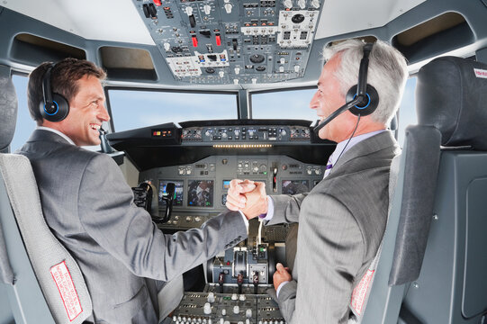 Pilots in suit celebrating teamwork inside airplane cockpit