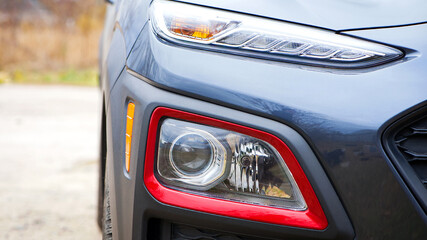 headlight of modern prestigious car closeup. beautiful headlights of a car. dark gray color, red...