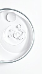 Clear liquid in petri dish, droplets, on white backdrop