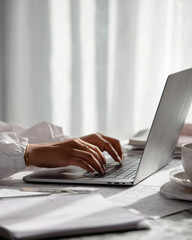 working from home with laptop and notes, focused writing and typing at desk, modern remote work lifestyle
