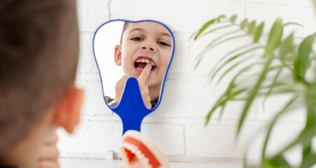 A boy looks into a mirror in the shape of a tooth and shows which tooth hurts.