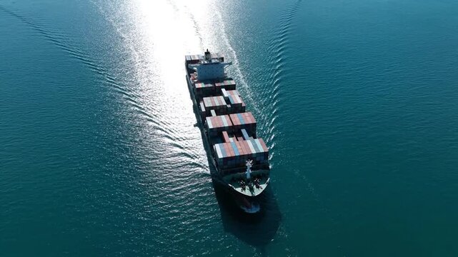 high detail aerial drone shot directly above a cargo ship traveling steadily across calm blue sea with realistic water texture and lighting
