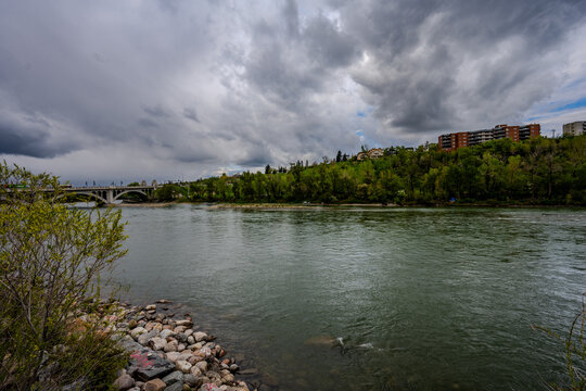 Riverbank with bridge and residential buildings under stormy sky - Powered by Adobe