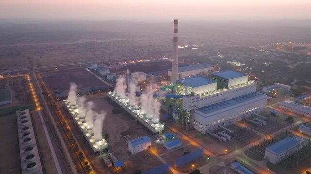 Right aerial orbit capturing the Thar Coal Power Plant just before full sunrise, with a bright sky illuminating the active steam vents and industrial infrastructure.