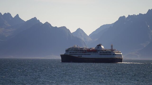 Ferry sails across calm sea with Lofoten mountains behind