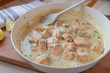 Delicious cubed salmon with  dill cream sauce in a skillet fresh and homemade cooked