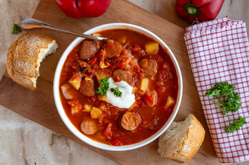 Delicious homemade Sauerkraut Soup with bell peppers, potatoes, tomatoes and krakauer sausage on a plate