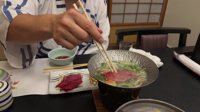 Young man in a traditional yukata eating a kaiseki shabu shabu dinner at a Japanese ryokan