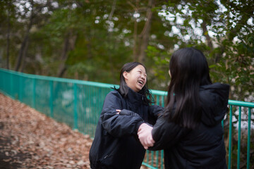 冬の朝の公園で楽しく散歩しながら遊んでいる女子中学生姉妹の姿