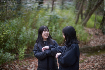 冬の朝の公園で楽しく散歩しながら遊んでいる女子中学生姉妹の姿