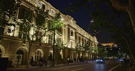 Lined Trees and Warmly Lit Building Creating Serene Night Atmosphere