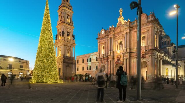 Timelapse video of people strolling through Piazza Bartolo Longo in Pompeii during the Christmas season. The Shrine of Our Lady of the Holy Rosary is illuminated with festive lights, highlighting the 