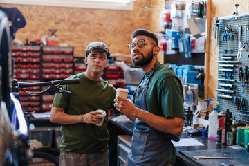 Mechanics taking a coffee break in bicycle workshop