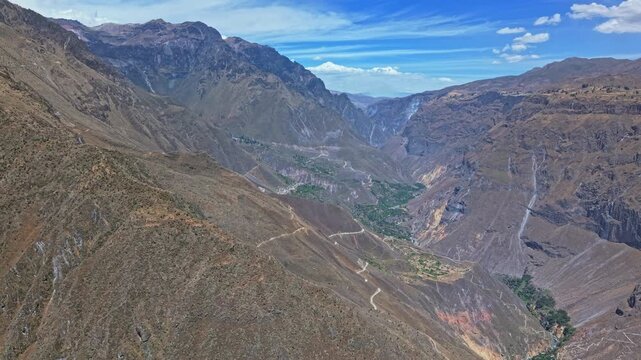 Dramatic pan past a Ridgeline reveals the staggering scale of Colca Canyon at its widest point. Vast distance between canyon walls and the endless depth below highlight canyons immense size and detail