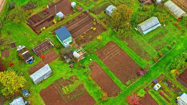 Aerial view of cultivated allotments and greenhouses on gloomy autumn day