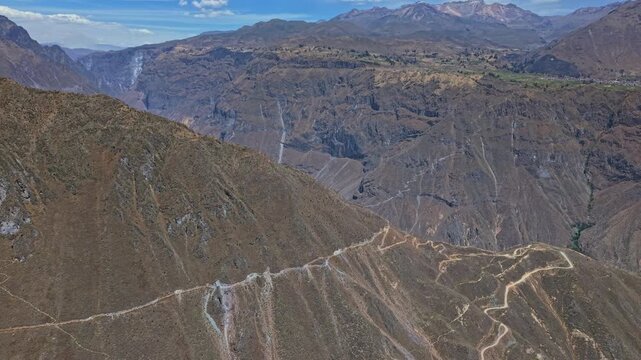 Drone flies from behind Colca Canyon&rsquo;s mirador, revealing canyon and emphasising the Cabanaconde rim. The immense drop and rugged cliffs showcase canyon&rsquo;s epic scale and dramatic Peruvian landscape.