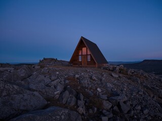 Small wooden cabin on rocky terrain at dusk