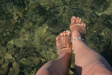 Relaxing at a resort by the sea with feet in clear water on a warm day