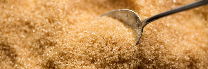 Brown Cane sugar in a spoon close up. Heathy eating, diet concept. Brown sugar background, texture. Top view, flat lay, food backdrop  