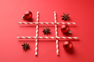 Tic tac toe game made with Christmas balls and anise stars on red background