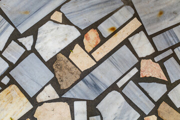 Natural stone mosaic pavement with irregular marble tiles in beige and white tones, textured outdoor floor background