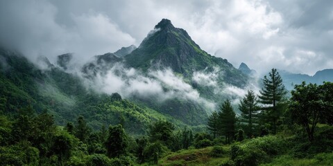 Lush green mountains shrouded in mist under a cloudy sky, showcasing a dramatic natural landscape