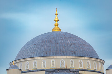 Elegant mosque dome with golden finial and geometric windows against a clear blue sky, showcasing Islamic architectural symmetry