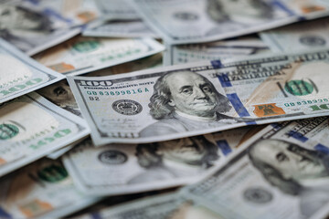 Close-up view of multiple hundred dollar bills stacked together, showcasing intricate details of currency design, texture, and vibrant colors in a financial context