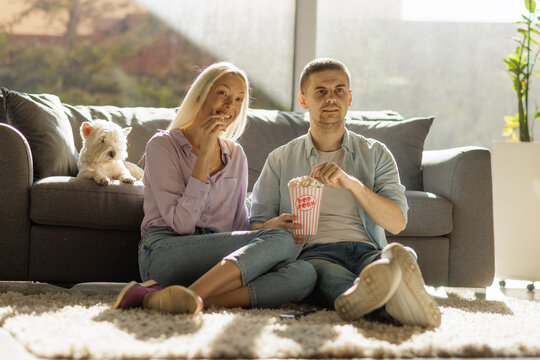 Couple sitting on a carpet and enjoying popcorn
