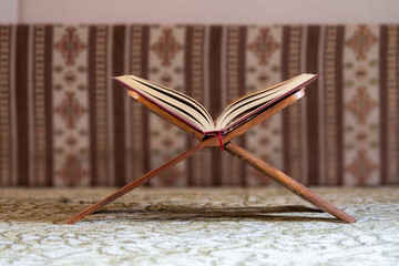 Open Quran on a wooden rehal stand inside a mosque, symbolizing Islamic worship, faith, and spiritual reflection
