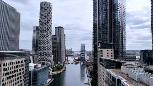 Backward aerial view along an urban river, rising to reveal modern skyscrapers. Cinematic drone shot showing contemporary architecture, glass towers and a metropolitan city skyline.
