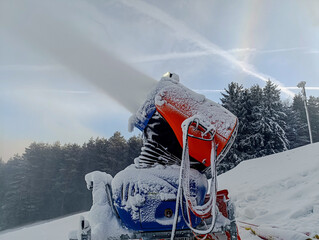 Snow cannon covering a ski slope with artificial snow for winter sports