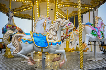 Carved carousel horses decorated with bright lights and colorful saddles