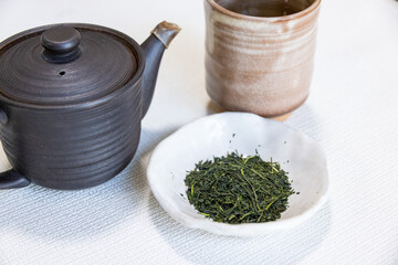 緑茶の茶葉と急須と湯呑みが並ぶ日本茶のセット