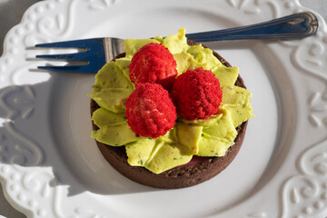 a gourmet tartlet featuring a dark chocolate crust filled with piped light green pistachio cream,...