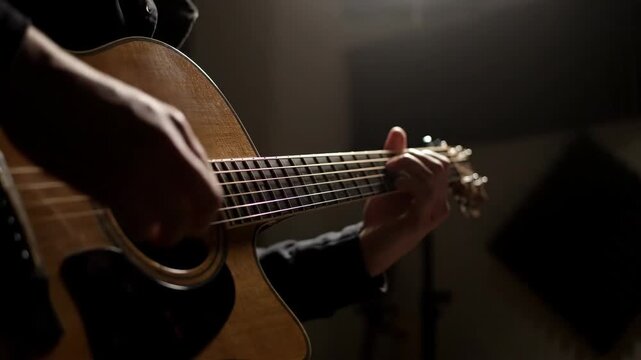 Close up of hands playing acoustic guitar in dim light