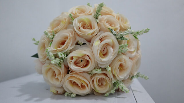 A spherical bouquet of peach roses with white and green fillers, ideal for weddings and romantic events