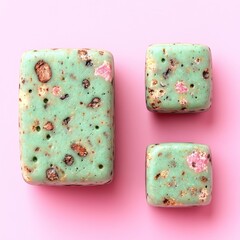 Colorful homemade soap shapes arranged on a soft pink background for a creative display