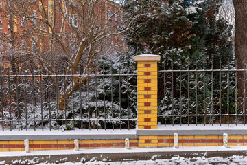 Charming snowy scene with a decorative fence and winter landscape in an urban park