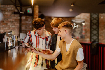 Three young friends gather around a table in a lively cafe, eagerly looking over the menu. Laughter...