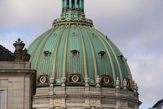 Close-up of a green domed roof with gold decorations on the round windows