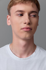 Fototapeta premium Young man face expression in a white t shirt under studio light, close up with neutral pose and calm mood, conveying clean aesthetic and minimal background