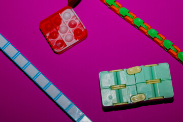 A bright silicone pop-it, an infinity cube, and flexible fidget chains are harmoniously arranged on a rich purple background.