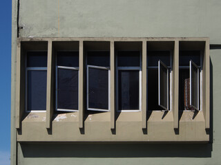 Green painted exterior of a shop building with rectanle shape casement windows.