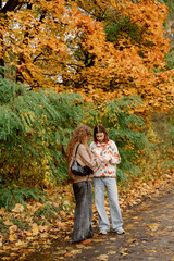 Two friends chat and laugh on a autumn day, surrounded by vibrant orange and yellow leaves. The serene setting invites moments of connection and joy in nature.