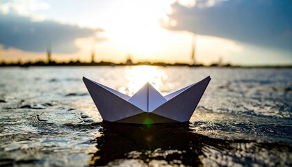 Paper boat sailing on water at sunset with blurred background.
